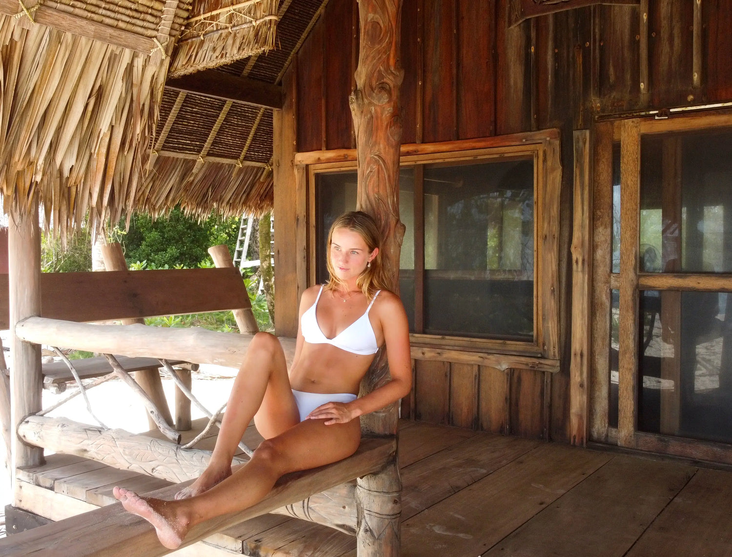 Woman sitting on a post wearing Bindi Swim Top and Tau Swim Bottom in White